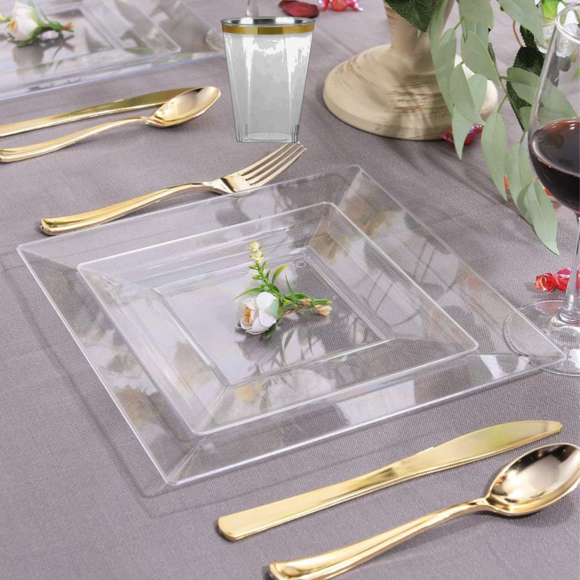 Clear square glass plate with gold cutlery on a gray tablecloth