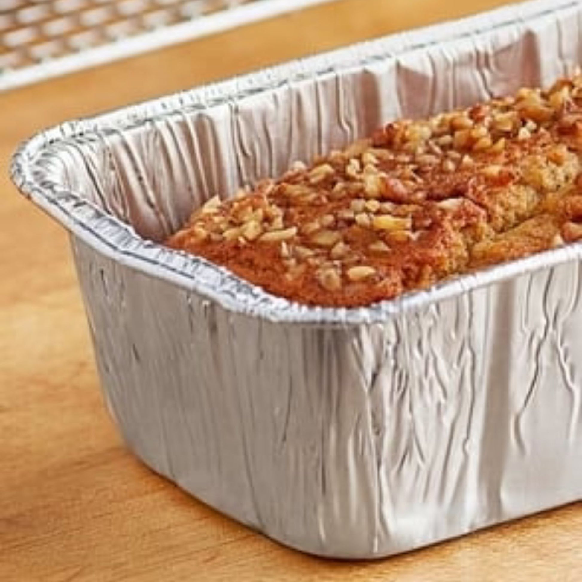 Loaf of bread in a foil pan on a wooden surface