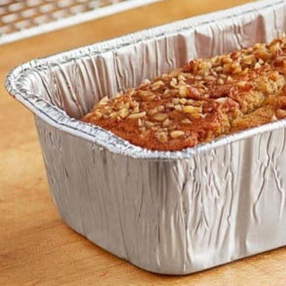 Loaf of bread in a foil pan on a wooden surface