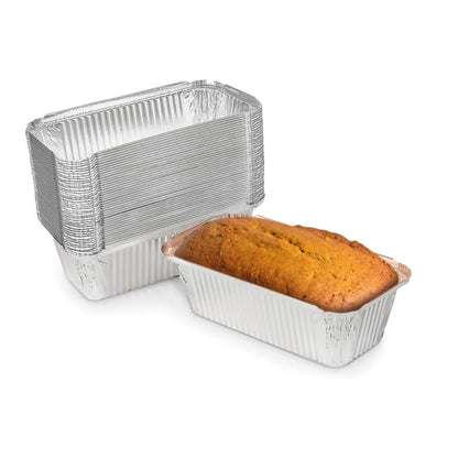 Aluminum loaf pans with a baked loaf of bread on a white background