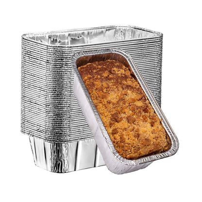 Aluminum loaf pans with a baked loaf of bread on a white background